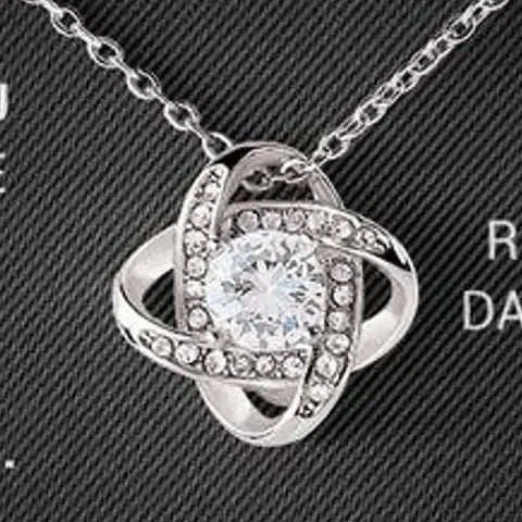 Close-up of the silver-tone love-knot pendant with its clear faceted stone